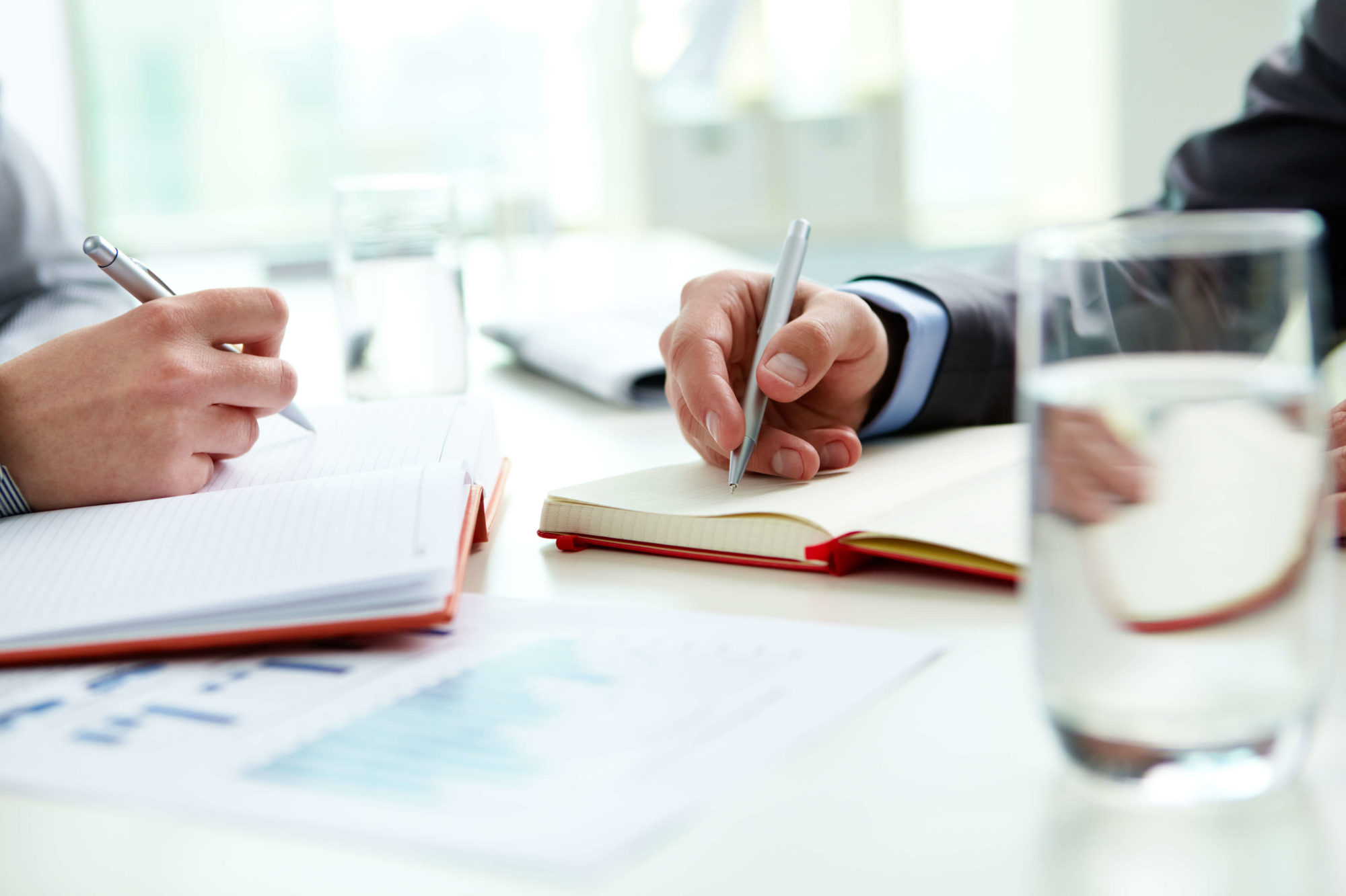 Photograph of a male and female hand writing in a notebook